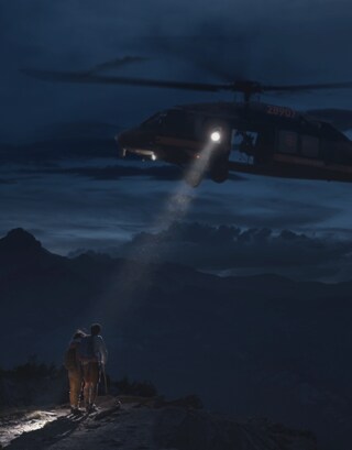 Dos personas siendo rescatadas de una montaña lejana por los servicios de emergencia.