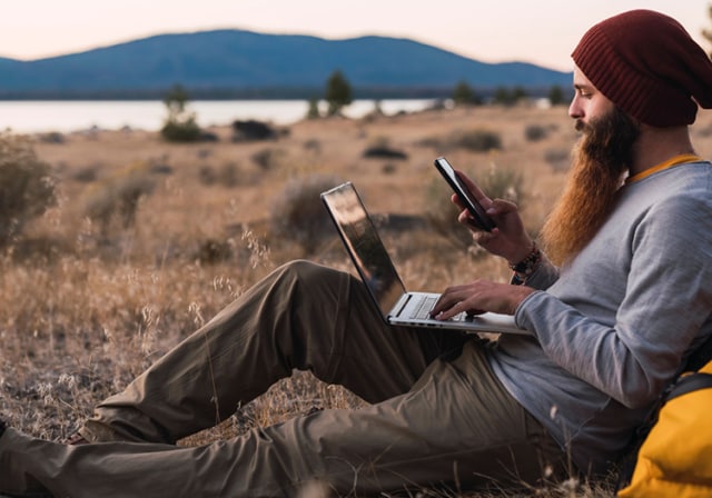 Un hombre conectándose a Internet en plena naturaleza a través de un dispositivo con hotspot.