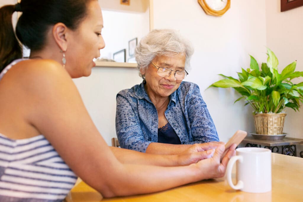 Middle aged woman showing phone to older woman