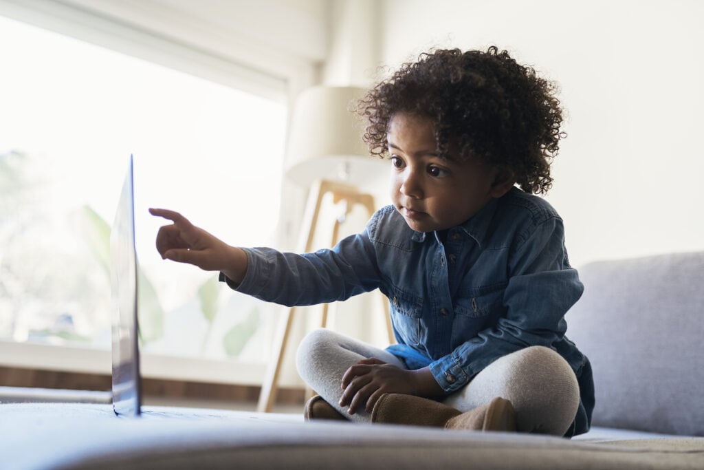 Portrait of beautiful racially-mixed child using laptop at home.