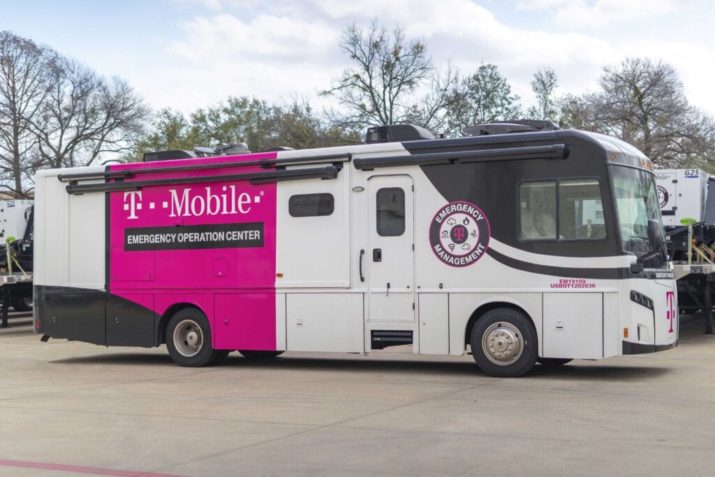 Large motorhome style RV parked outdoors. Vehicle is branded with the T-Mobile logo and the title of Emergency Operation Center