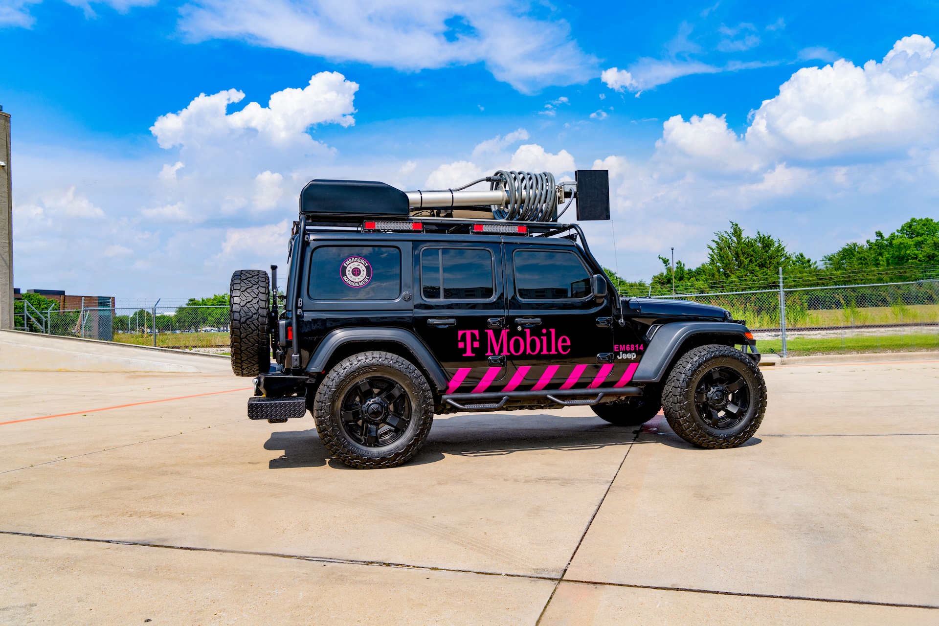 T-Mobile logo branded all-terrain vehicle with mounted satellite equipment retracted to convey portability. Vehicle is parked outdoors.