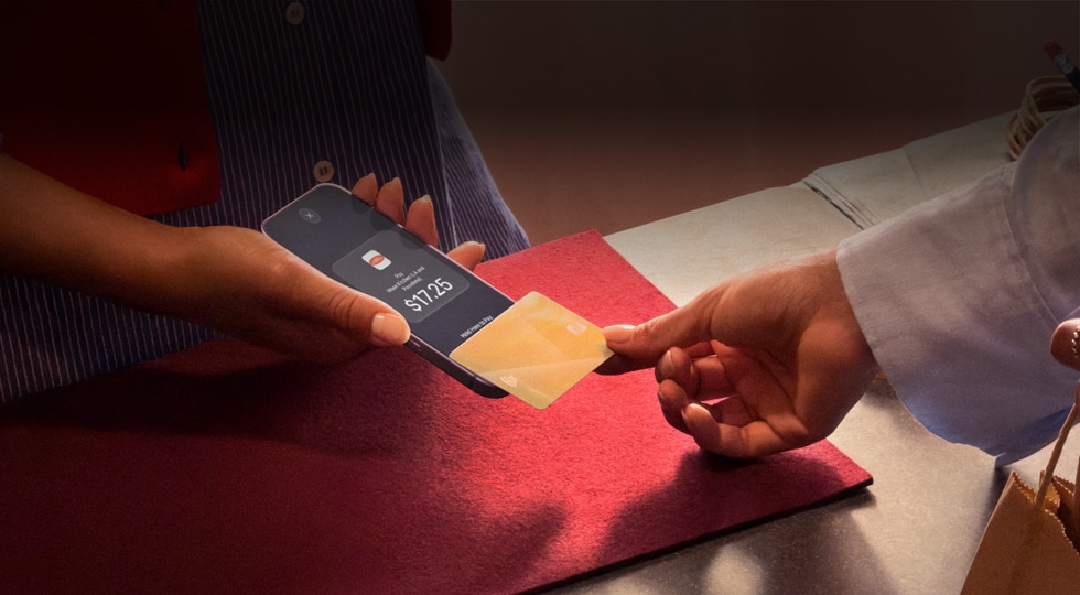 Una mano acerca una tarjeta de crédito a un iPhone para completar un pago
