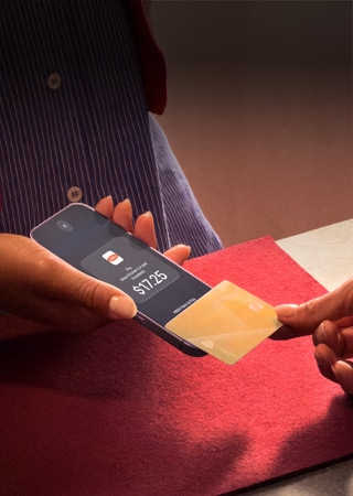 Una mano acerca una tarjeta de crédito a un iPhone para completar un pago