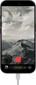 iPhone 18 Pro, vista frontal exterior, se muestra un paisaje montañoso, con la superposición del modo de cámara en modo Time-Lapse, y el cable de alimentación conectado al puerto de carga