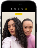 iPhone 18 Pro, negro, exterior frontal, muestra a dos modelos posando para la cámara, donde se aprecia la cámara frontal Center Stage