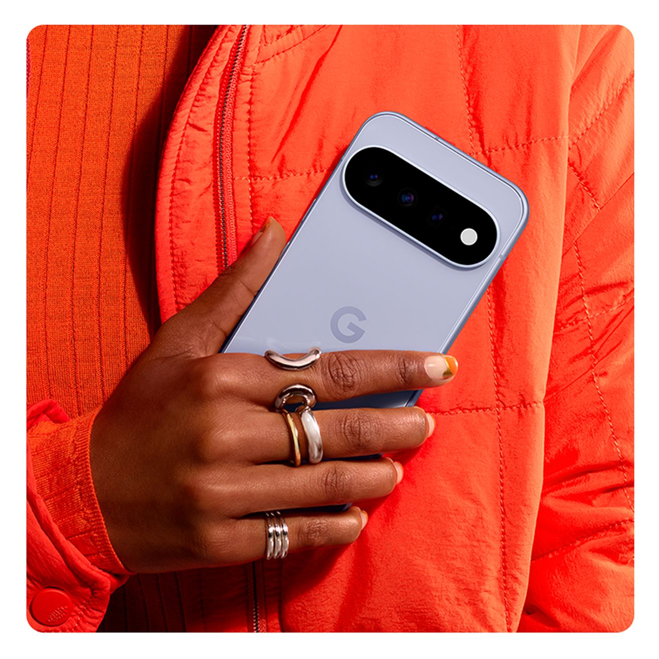 Primer plano de una persona sosteniendo un teléfono Google Pixel 11 Pro XL frente a un suéter naranja