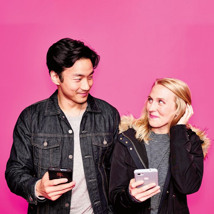 Hombre y mujer sonrientes sosteniendo sus smartphones sobre un fondo magenta.