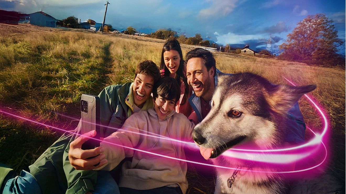 Cuatro personas y un perro husky se toman un selfie al aire libre.