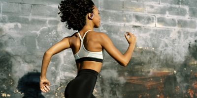 Woman running past a brick wall.