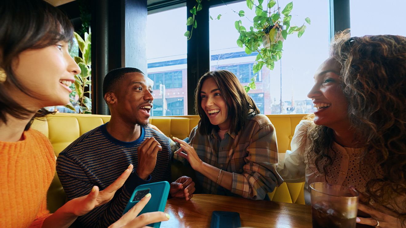 Cuatro amigos riendo en la mesa de un restaurante