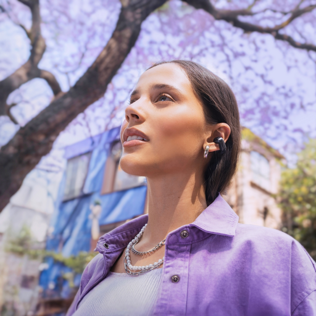 Mujer escuchando música al aire libre con los audífonos abiertos Bose Ultra.