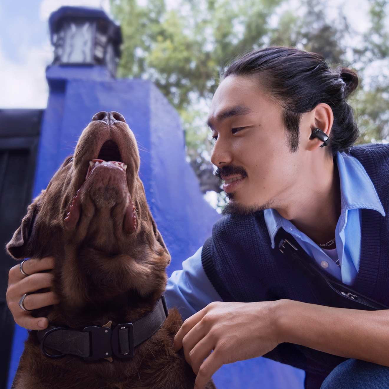 Hombre con su perro usando audífonos abiertos Bose Ultra.