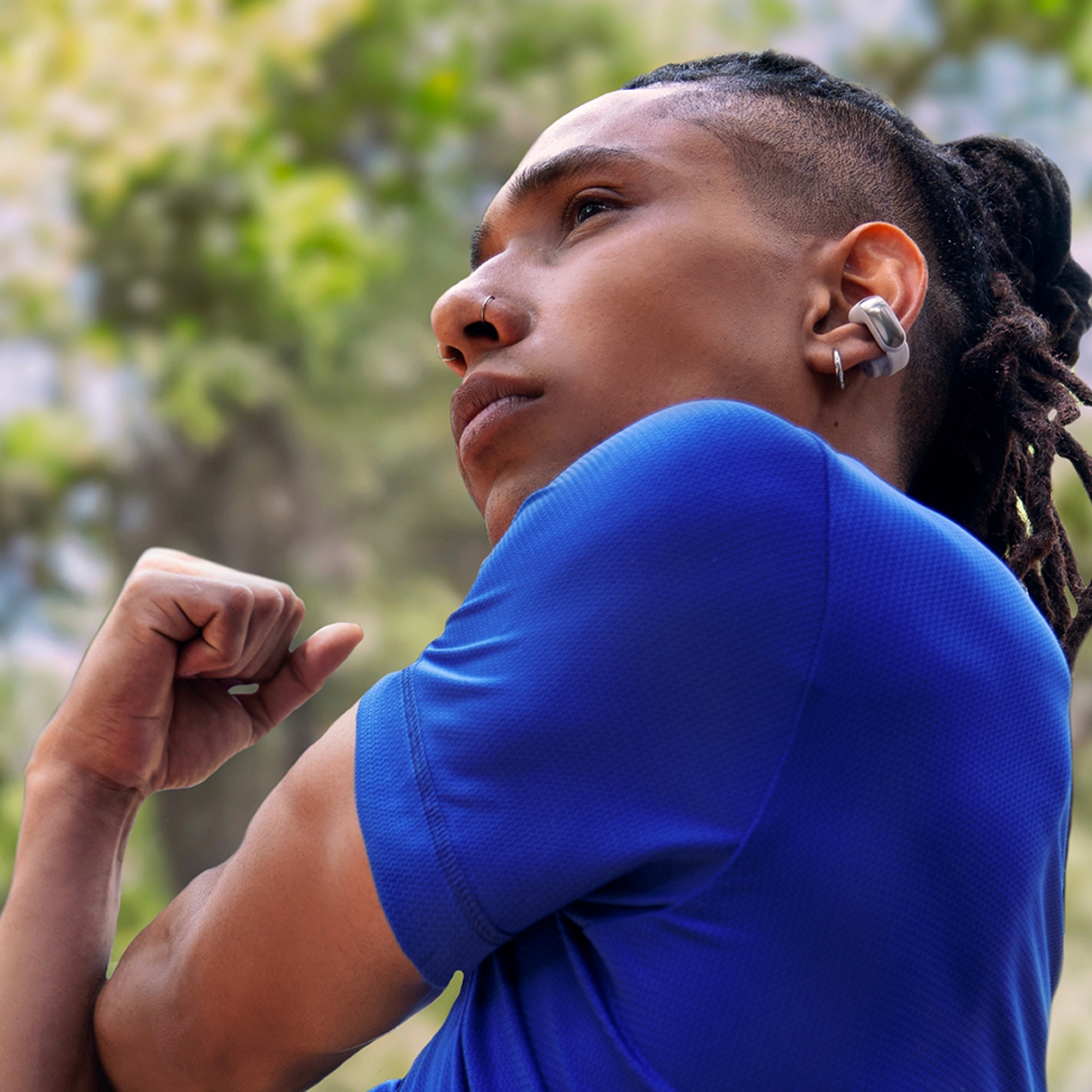 ​​​​​​​Hombre haciendo estiramientos mientras lleva puestos los audífonos abiertos Bose Ultra.