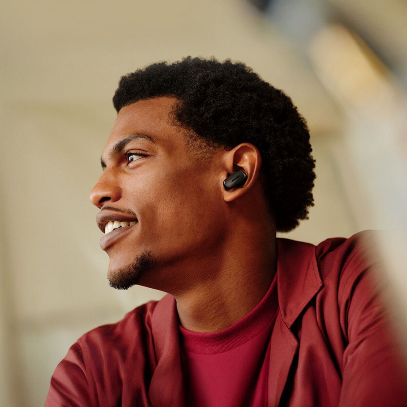 Un hombre con una camiseta roja disfruta escuchando música con sus audífonos Bose Quiet Comfort Ultra de segunda generación.