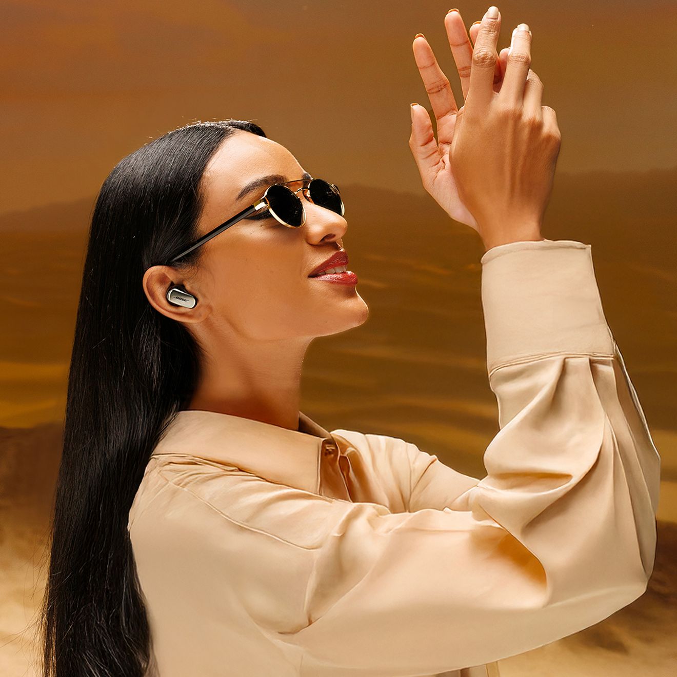 Una mujer con gafas de sol está al aire libre disfrutando de sus audífonos Bose Quiet Comfort Ultra de segunda generación.