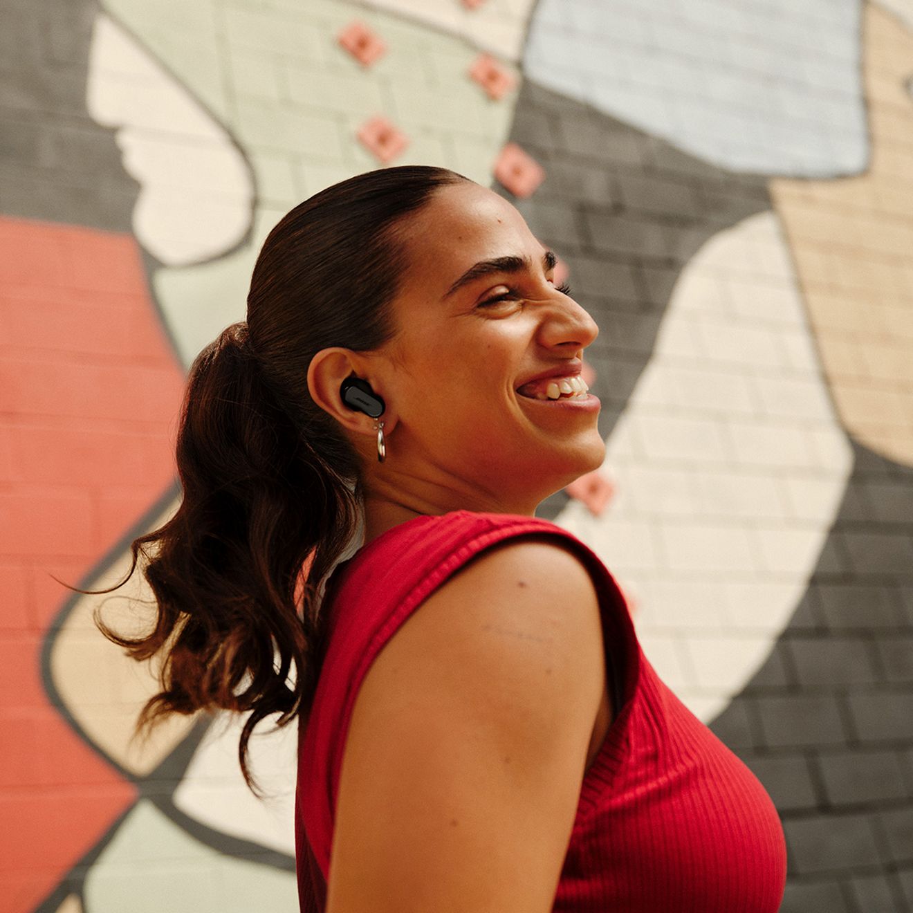 Una mujer sonríe al aire libre mientras usa sus audífonos Bose Quiet Comfort Ultra de segunda generación.