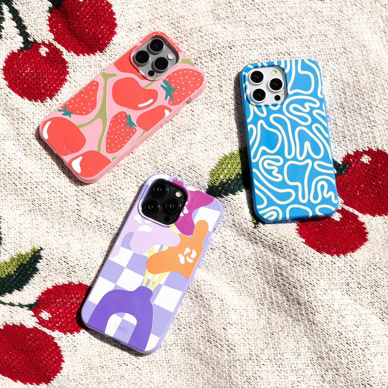 Hay un grupo de tres fundas Pela para iPhone colocadas sobre una manta.
