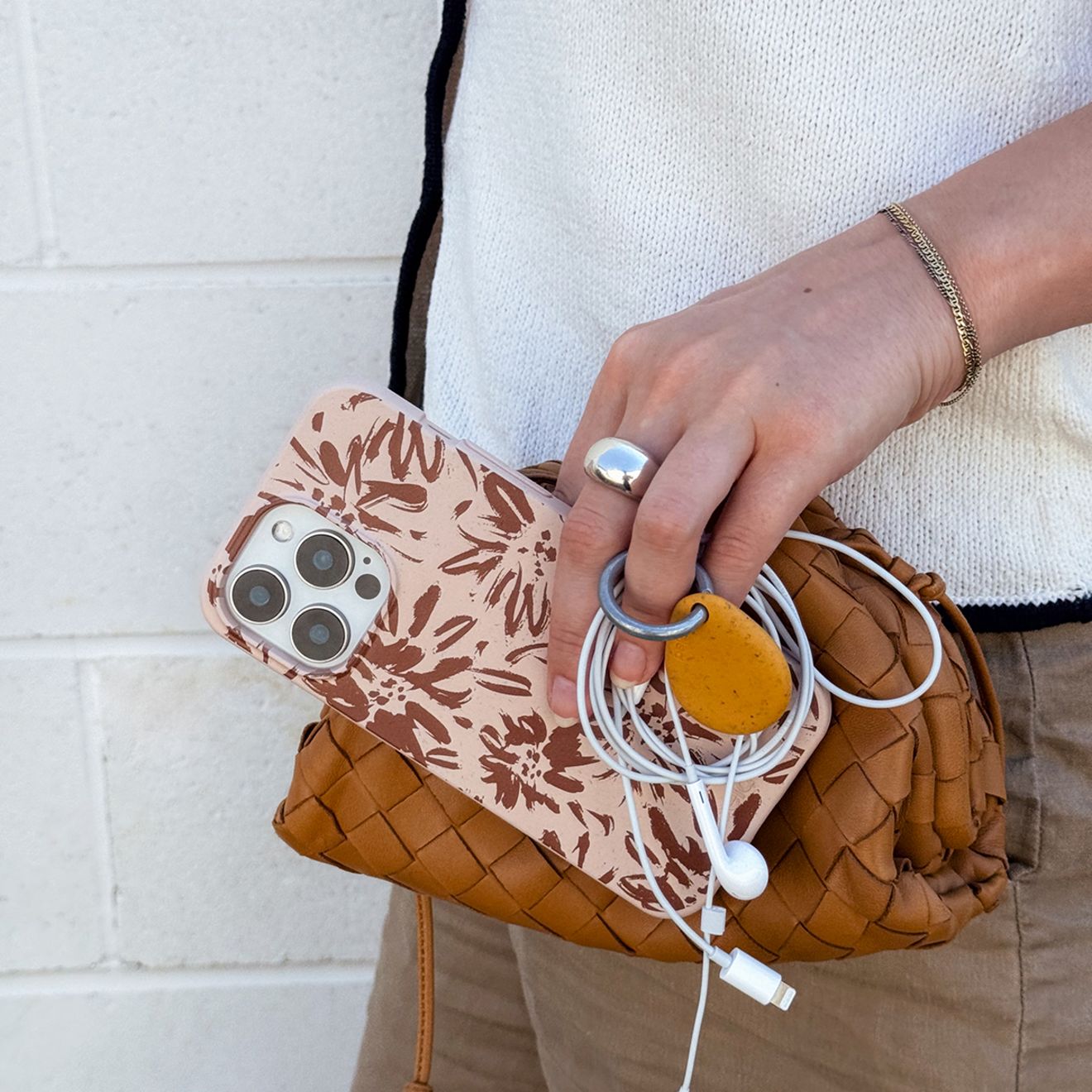 Un hombre sostiene su funda Pela para iPhone y los audífonos de su iPhone.