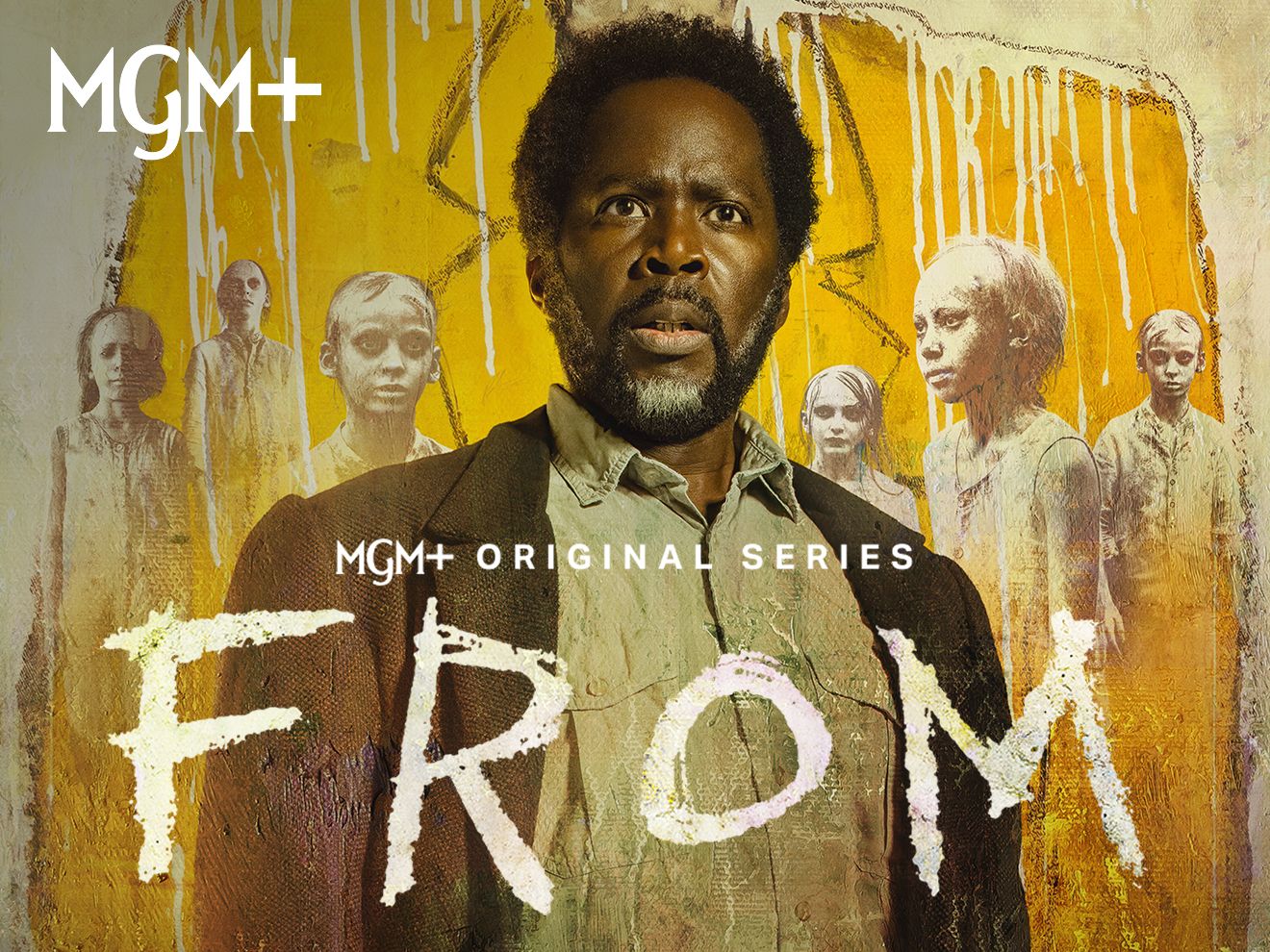 El actor Harold Perrineau, protagonista de la serie original de MGM+ titulada “From”. Detrás de él, hay un cartel con un traje amarillo y unos personajes inquietantes de la serie.