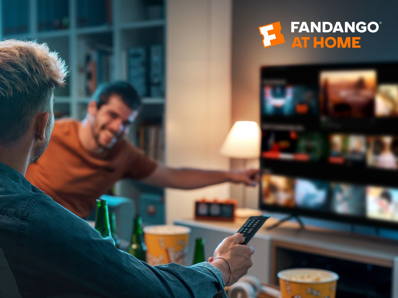 Dos amigos en casa eligen una película en la TV para verla con Fandango at Home.