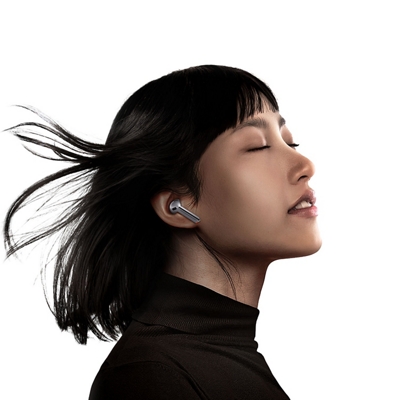 Una mujer con el pelo al viento cierra los ojos mientras escucha sus Galaxy Buds3.