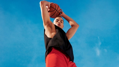 Un hombre al aire libre sosteniendo una pelota de básquetbol sobre su cabeza