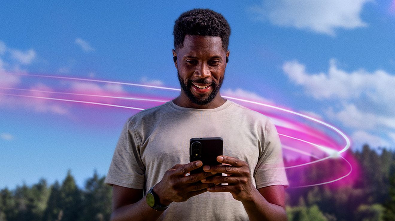 Magenta beams swirl through the blue sky toward the phone a man holds as he walks in nature.