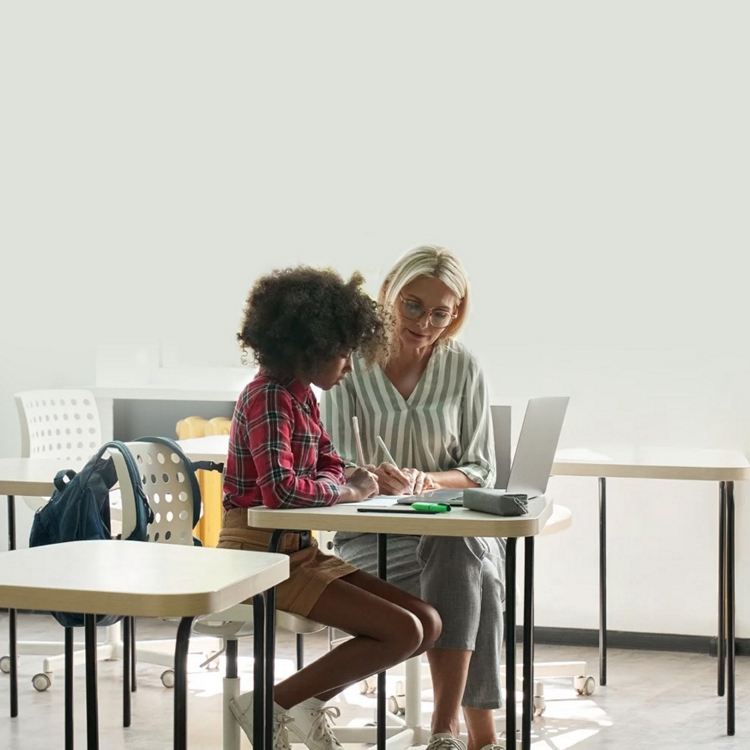 Una maestra ayuda a una alumna en un aula.