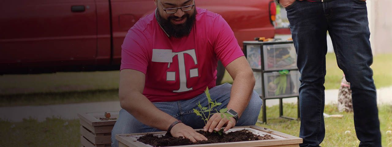 Empleado de T-Mobile plantando un jardín durante un evento voluntario.