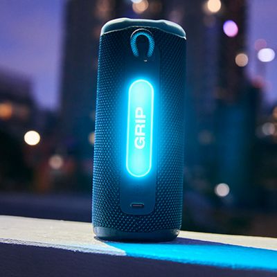 Una JBL Grip iluminada de azul por la noche.
