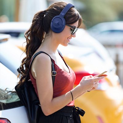 Una mujer con audífonos JBL Tune 780NC mira su teléfono.