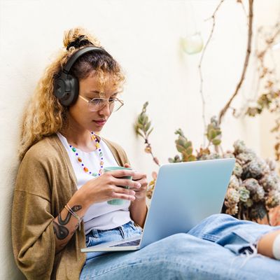 Una mujer mira su laptop mientras lleva puestos audífonos JBL Tune 780NC.