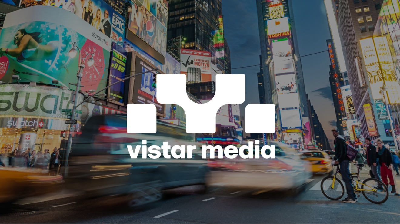 Busy city street lined with digital outdoor signage, cars, and people on bikes.