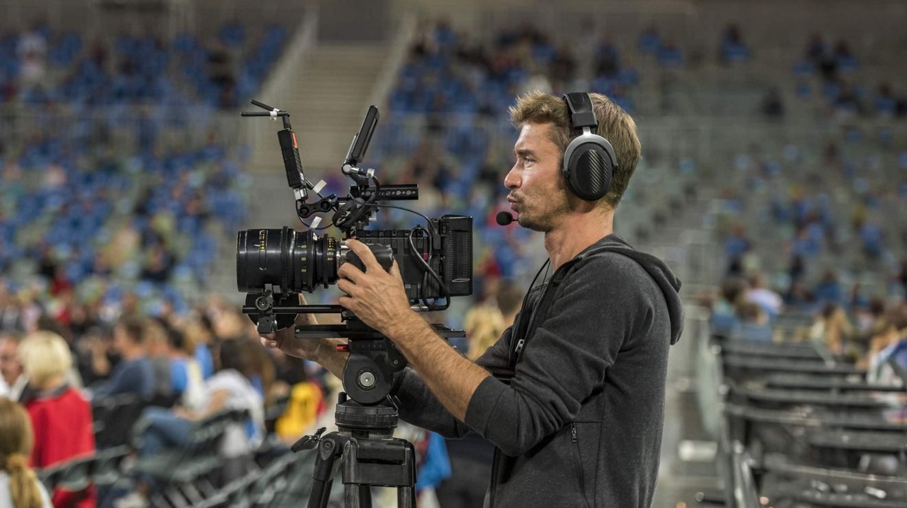 Persona operando una cámara de calidad profesional desde el piso de un estadio.