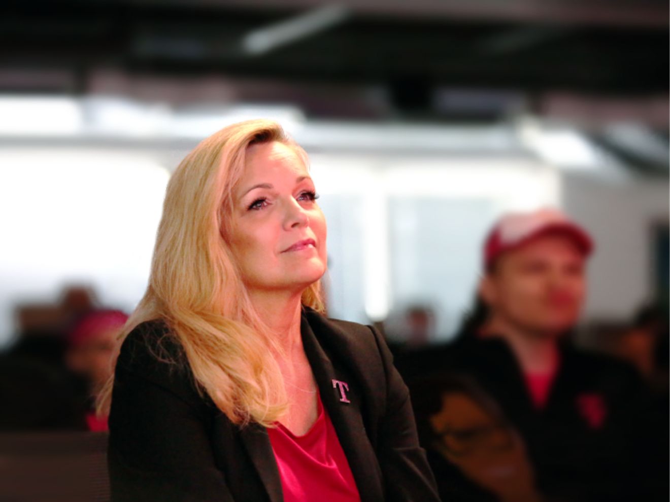 Janice sonríe. Detrás de ella hay una multitud de empleados de T-Mobile.