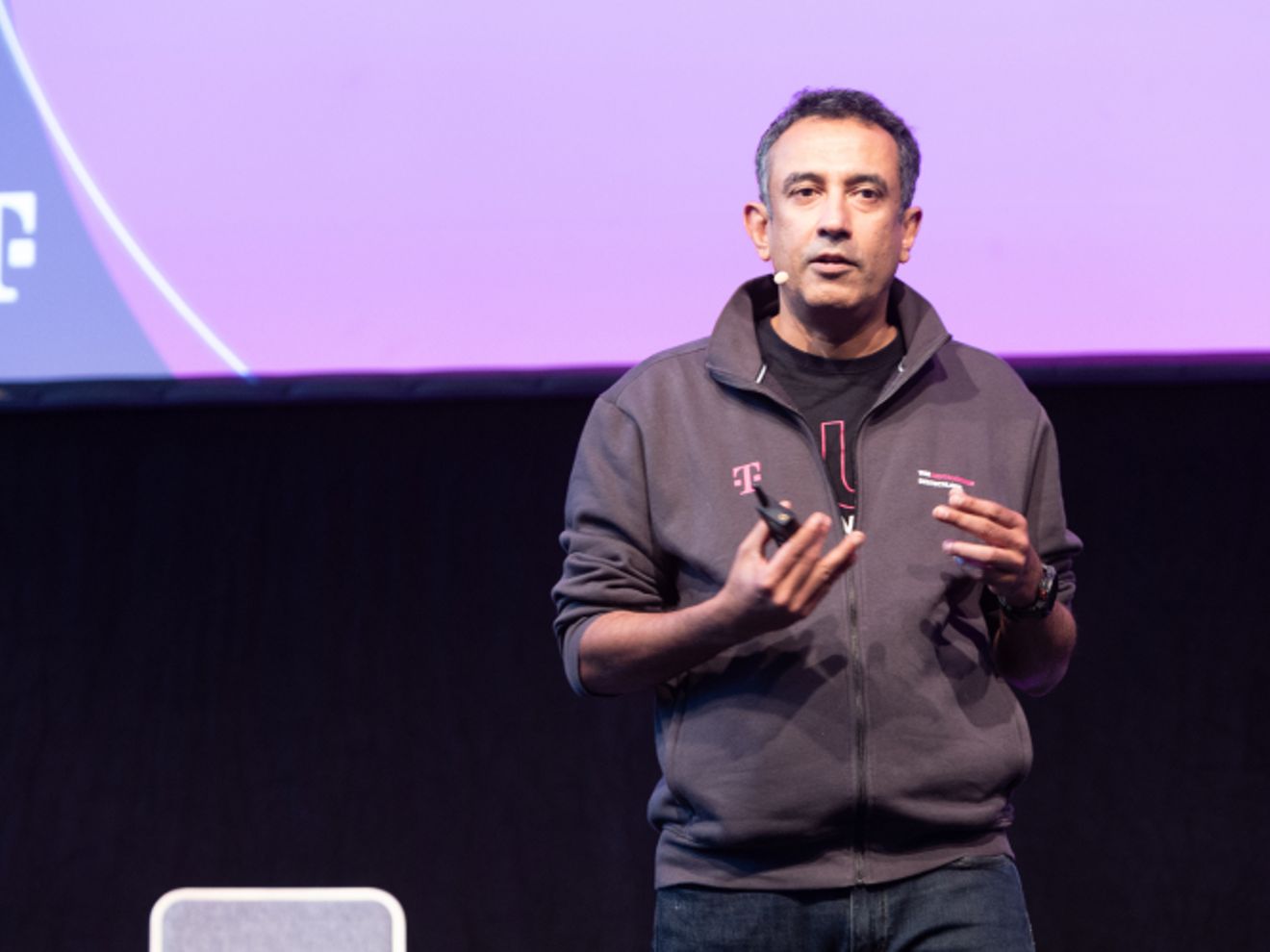 Srini en el escenario dirigiéndose a una multitud de empleados de T-Mobile.