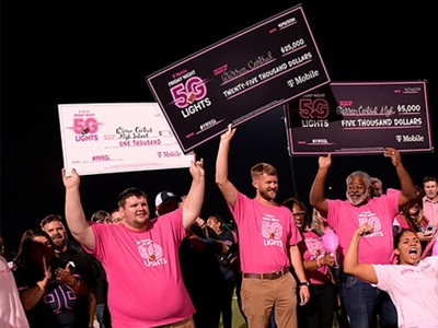 Un grupo de estudiantes vestidos de magenta sostienen grandes cheques en alto.