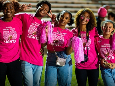 Un grupo de estudiantes vestidos de magenta sonríen a la cámara.