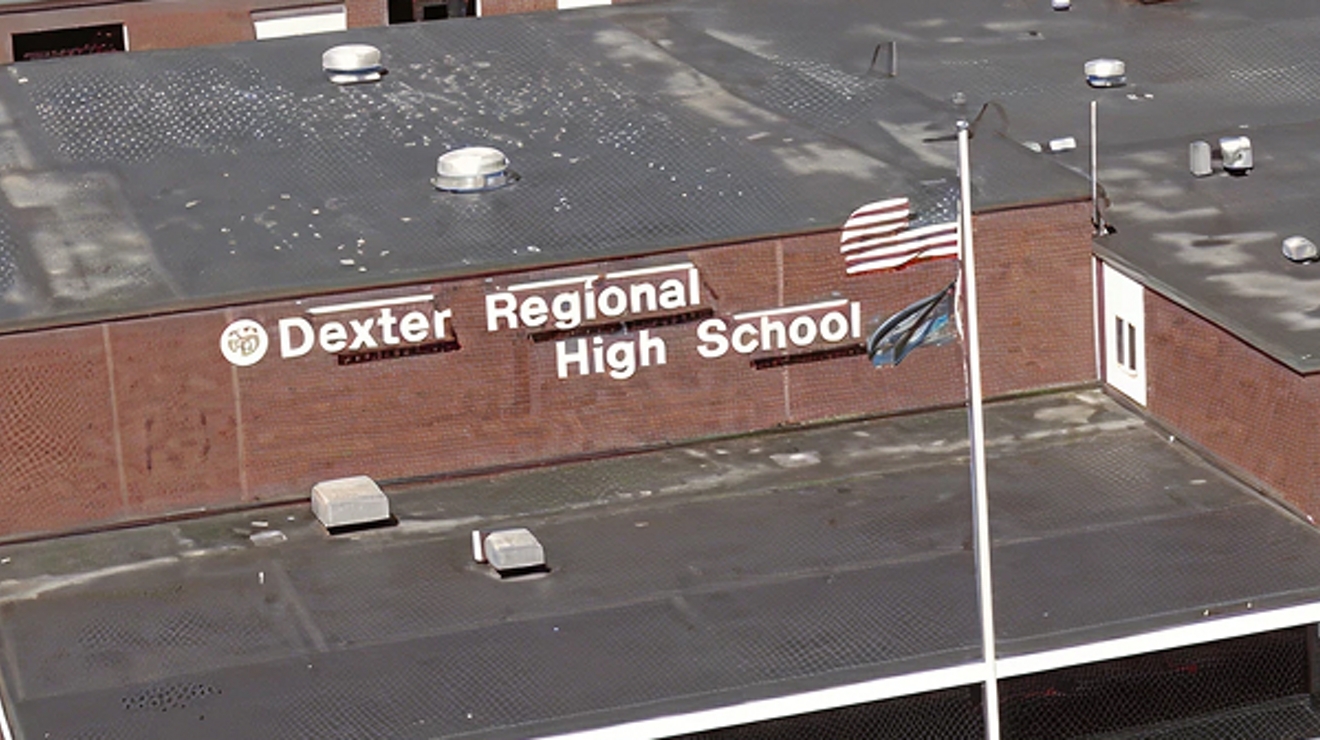 Vista aérea de Dexter Regional High School, un edificio color café con la bandera estadounidense en el frente.