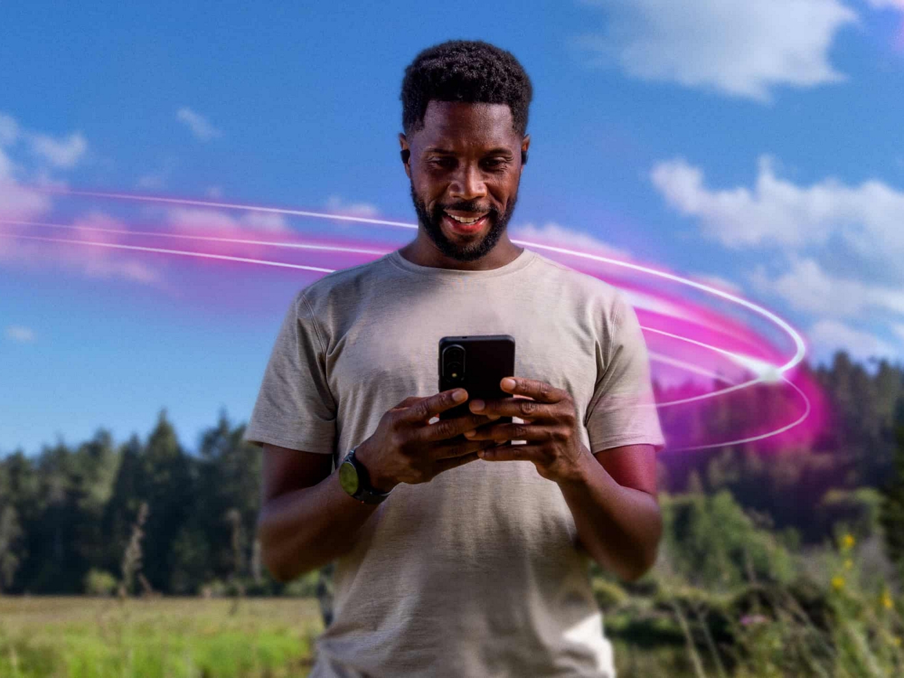 Un hombre atlético sonriendo mientras mira su teléfono en un día soleado