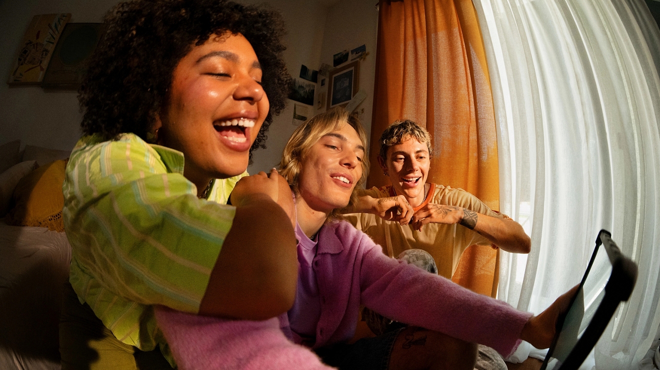 Un grupo de 3 jóvenes mira contenido en una tablet