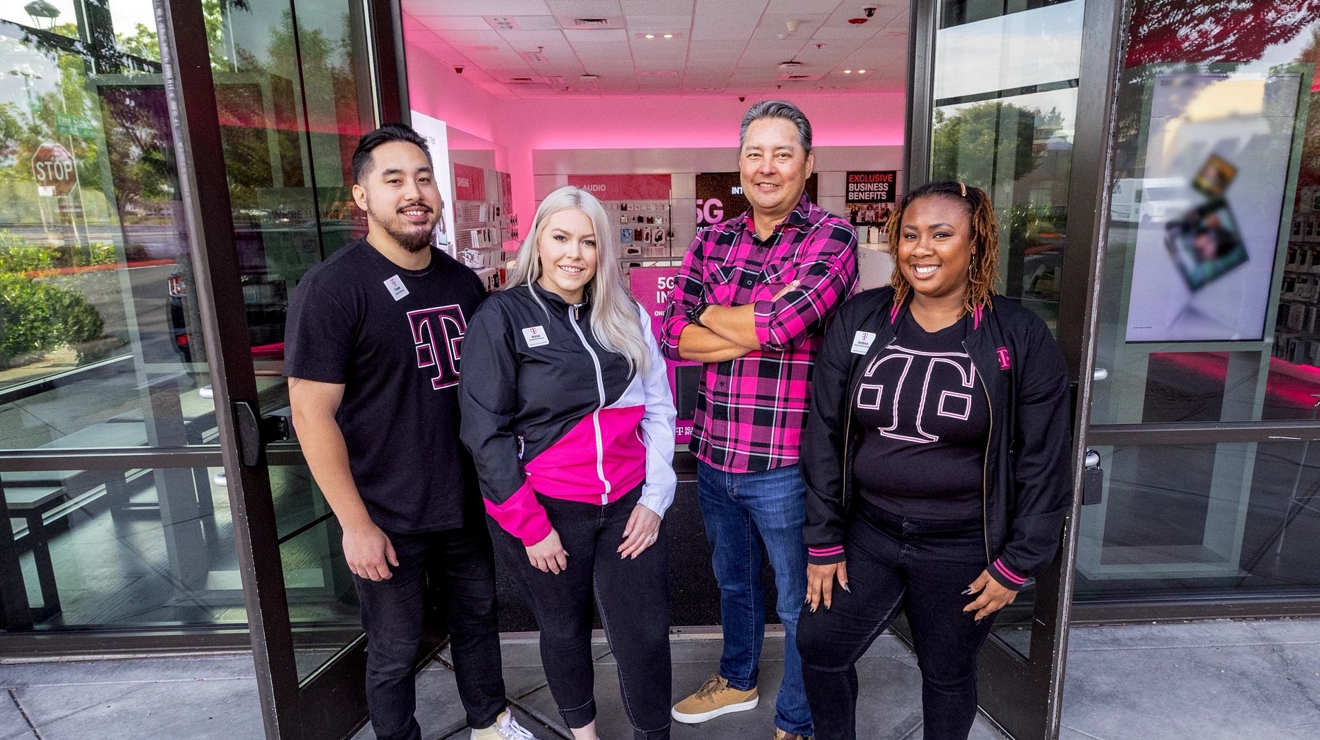 Un grupo de empleados de T-Mobile posando para una foto frente a una tienda T-Mobile