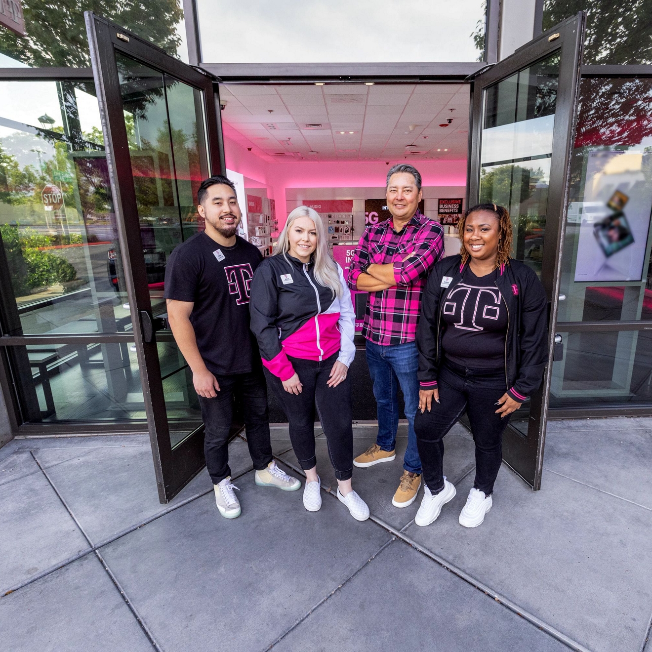 Un grupo de empleados de T-Mobile posando para una foto frente a una tienda T-Mobile