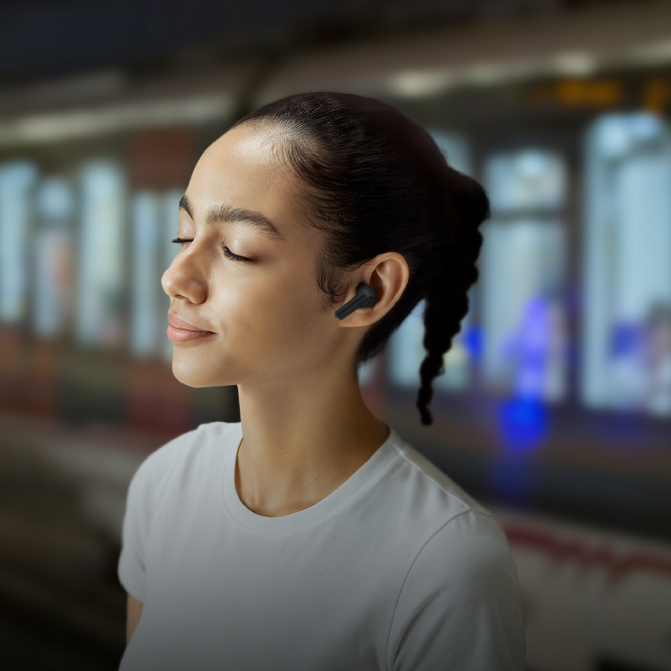 Persona escuchando Buds3 FE mientras pasa un tren al fondo