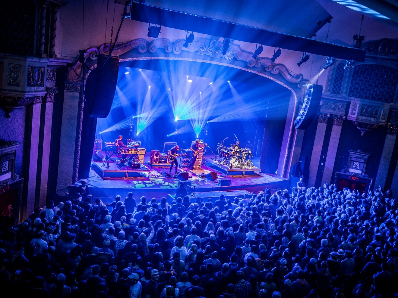 Una multitud disfrutando de la actuación en vivo de una banda en un recinto cubierto.