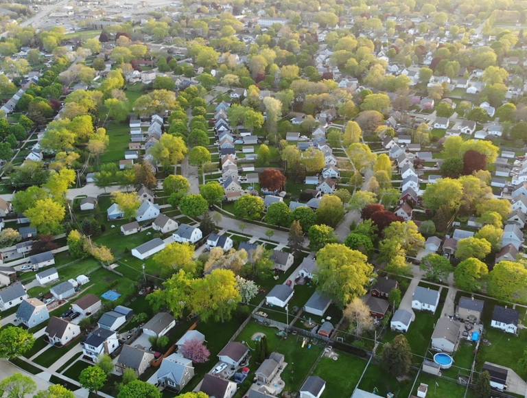Vista aérea de la comunidad con abundantes árboles rodeando las casas.