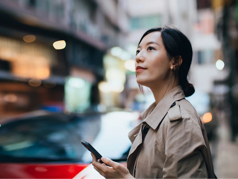 Persona utilizando un smartphone en una concurrida calle de la ciudad
