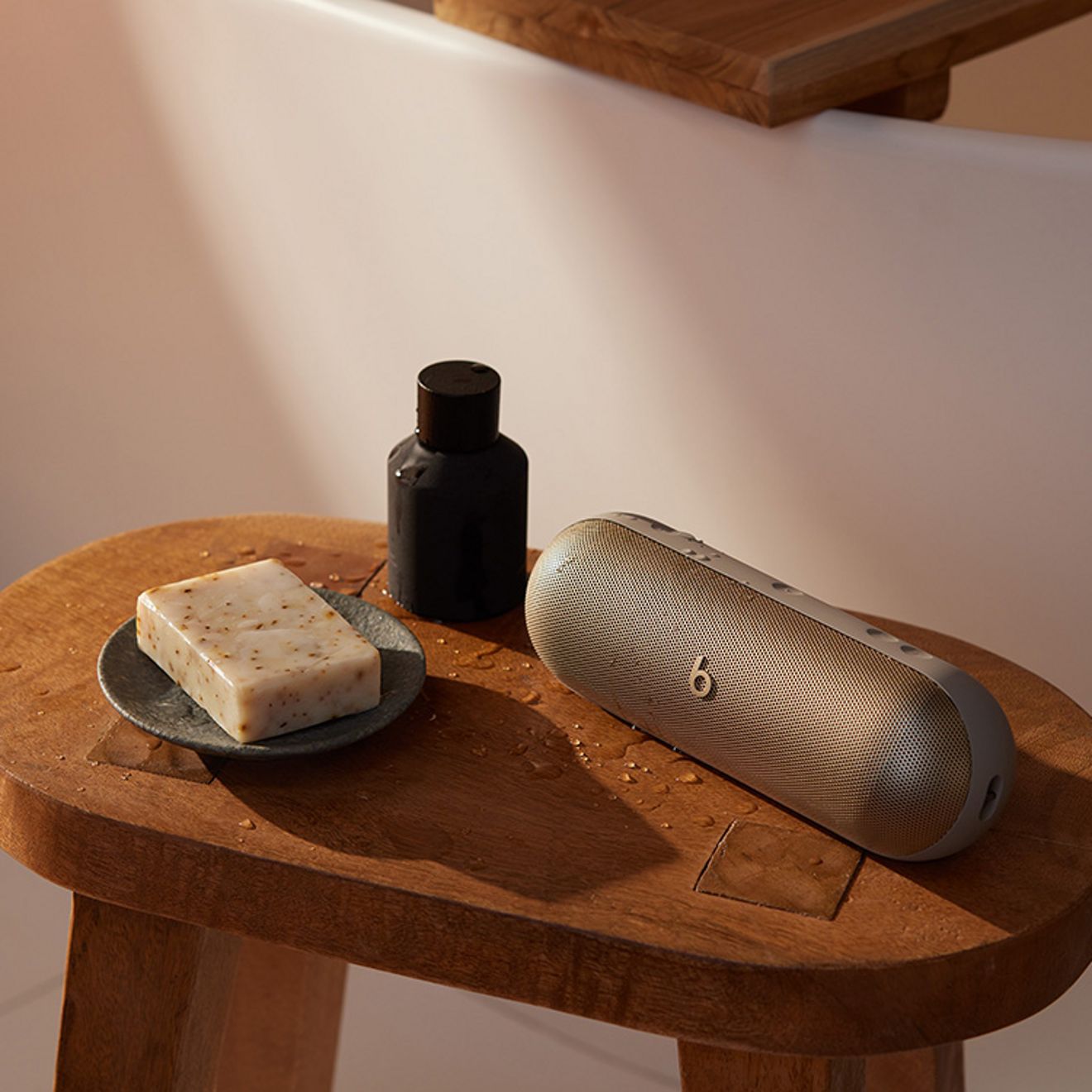 La bocina Beats Pill está sobre una mesita auxiliar junto con objetos de uso diario.