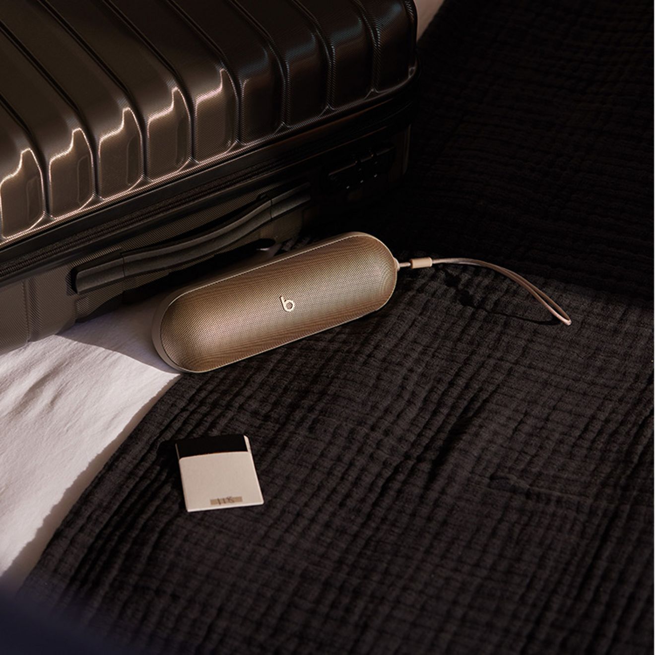 Una beats pill plateada junto a una maleta.